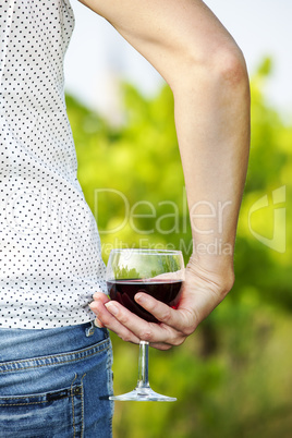 Woman with glass of red wine in vineyard