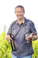 Man with wine bottle and glasses in vineyard