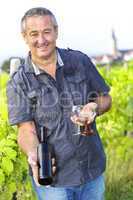 Man with wine bottle and glasses in vineyard