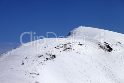 Snowboarders and skiers downhill on off piste slope at sun day