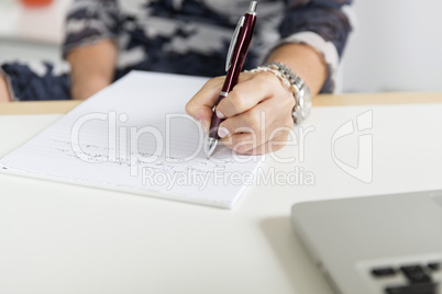 Hand (Frau) schreibend mit Kugelschreiber und Notizblock
