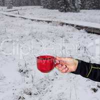 Hand holding in Winter Landscape cup with hot drink