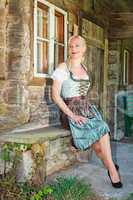 Bayerische blonde Frau sitzend elegant im Dirndl