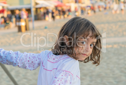 Baby playing on the beach at sunset and looking to the camera