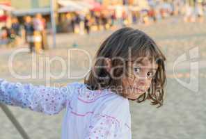 Baby playing on the beach at sunset and looking to the camera