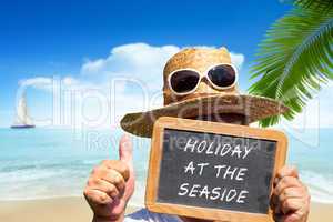 Mann hält Tafel mit Text: Holiday at the Seaside