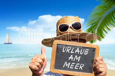 Mann hält Tafel mit Text: Urlaub am Meer