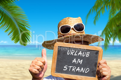 Mann hält Tafel mit Text: Urlaub am Strand