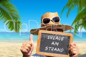 Mann hält Tafel mit Text: Urlaub am Strand
