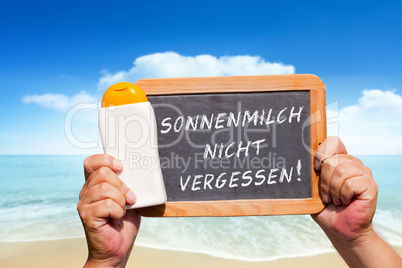 Hände halten Tafel mit Text: Sonnenmilch nicht vergessen