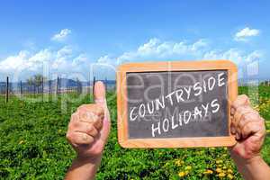 Hände halten Tafel mit Text: Countryside Holidays