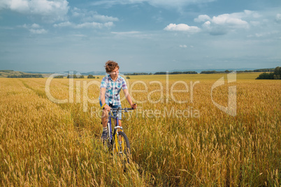Boy  on a bicycle on mellow rye field
