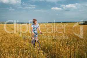 Boy  on a bicycle on mellow rye field
