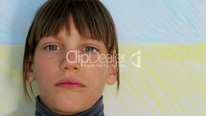 Sad little boy on a background of Ukrainian flag. .Boy looks at the camera,Child emotionally looking at the camera.