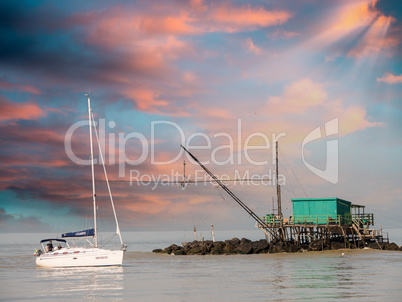 Colourful hut on the rocks at sunset with boat cruising the ocea