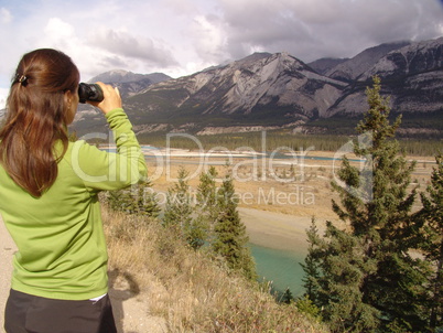 eine Frau schaut mit einem Fernglas in den Jasper Nationalpark