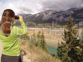 eine Frau schaut mit einem Fernglas in den Jasper Nationalpark
