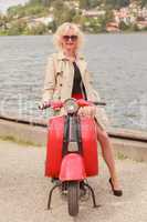 Blondes Model mit Sonnenbrille auf einem Motorroller