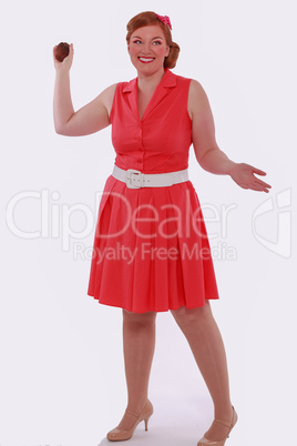 Rothaarige Frau im roten Kleid 60 Jahre Style und Übergewicht, wirft mit einem Muffin