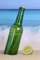 Bier in grüner Flasche am Strand und Meer