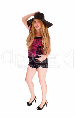 Woman in shorts and hat standing.