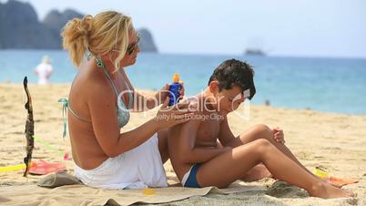 mother applying sunscreen to son