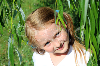 girl smiling besides the leaves of willow