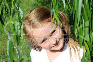 girl smiling besides the leaves of willow