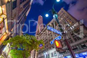 Fifth Avenue street sign at night with Manhattan buildings on ba