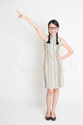 Full length Asian Chinese girl pointing on blank space