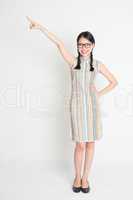 Full length Asian Chinese girl pointing on blank space