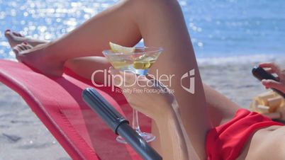 Bikini woman with cocktail glass relaxing on tropical beach close-up