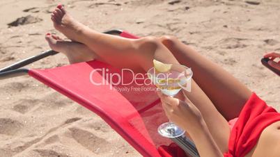 Bikini girl with cocktail relaxing on sandy summer beach