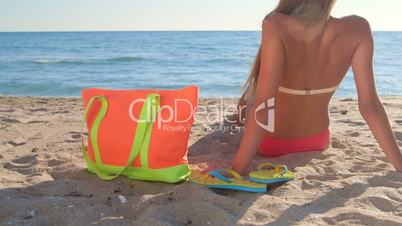 Bikini girl with colorful accessories on sandy beach