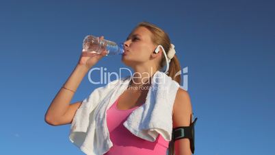Athletic girl drinks water after running and exercising outdoors