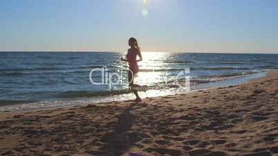 Silhouette of fitness athletic girl jogging along the beach