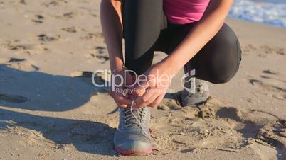 Fitness athletic girl lacing sport shoes before start jogging