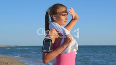 Fitness athletic girl with wireless headset and smart phone on the beach