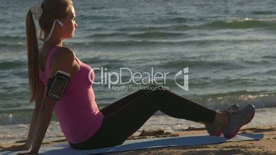 Fitness athletic girl exercising on the beach at sunset