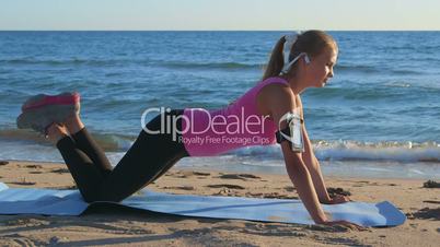 Fitness routine for women - athletic girl doing push-ups on beach