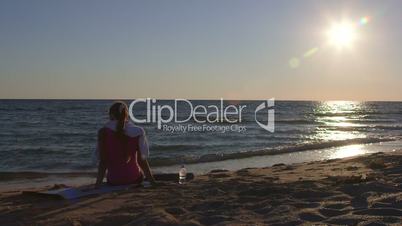 Fitness woman relaxing after workout routine listening music on beach