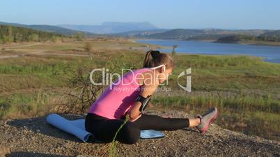 Fitness young woman stretching legs before exercise outdoors