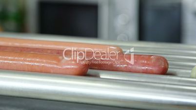 Sausages for hot dog are heated on rotating grills in fast-food diner