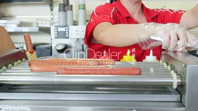 Woman employee prepares hot dogs in a fast food restaurant