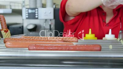 Woman employee prepares hot dogs in a fast food restaurant