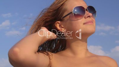 Face of cute girl in sunglasses on the beach against sky close-up