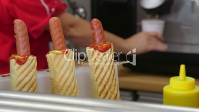 Employee making hot dogs and coffee cup in fast food lunch dinner