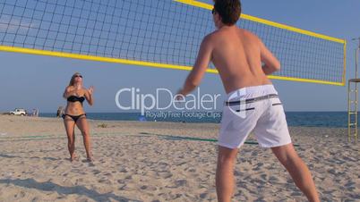 Teen couple playing volleyball on the beach