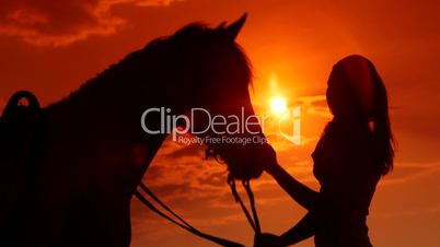 Young girl with her horse in rays of setting sun