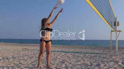 Young girl spends summer vacation on the beach playing volleyball